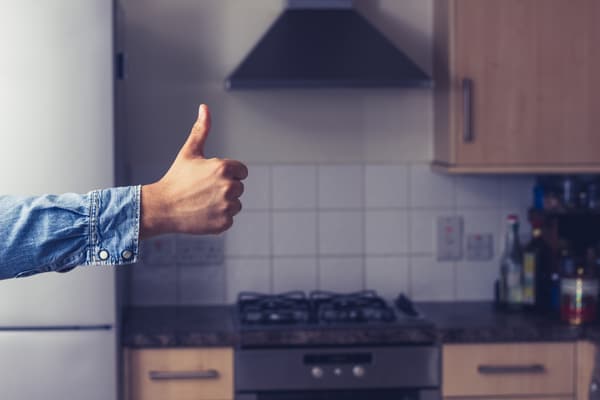 A person giving a thumb-up with appliances in the background